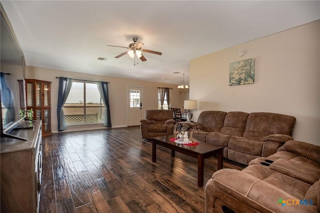 living area with dark wood-style flooring, visible vents, baseboards, and ceiling fan with notable chandelier