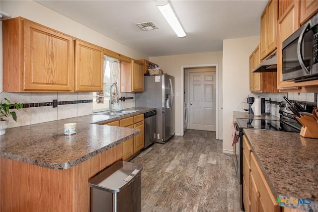 kitchen with visible vents, decorative backsplash, appliances with stainless steel finishes, wood finished floors, and under cabinet range hood