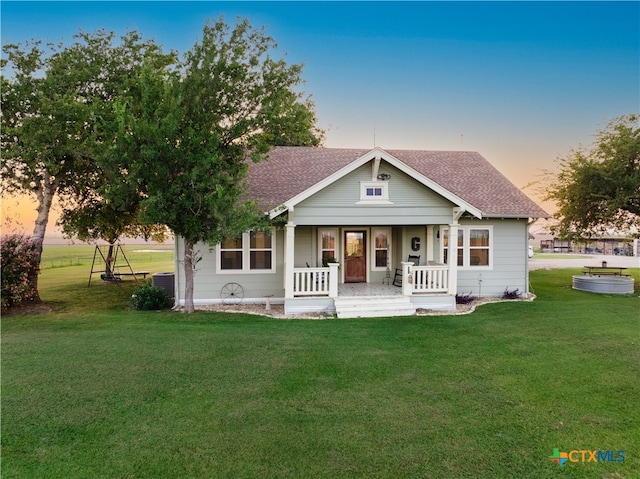 view of front of property with central air condition unit, covered porch, and a yard