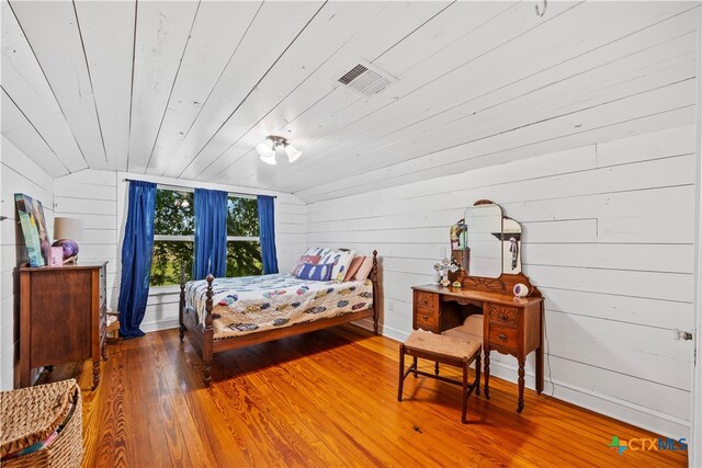 bedroom with hardwood / wood-style floors, lofted ceiling, wooden walls, and wood ceiling