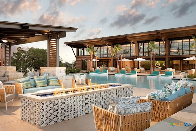 pool with an outdoor living space with a fire pit and a patio