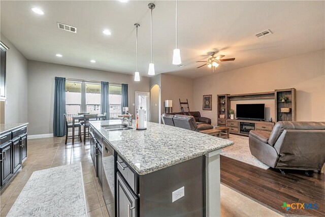 822 Old World Dr, Harker Heights, TX 76548 - kitchen with arched walkways, stainless steel dishwasher, ceiling fan, light stone counters, and a kitchen island with sink