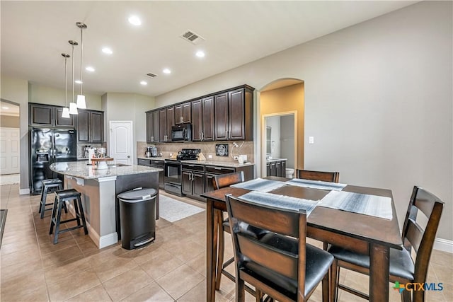 822 Old World Dr, Harker Heights, TX 76548 - kitchen featuring black appliances, decorative backsplash, arched walkways, a kitchen breakfast bar, and dark brown cabinets