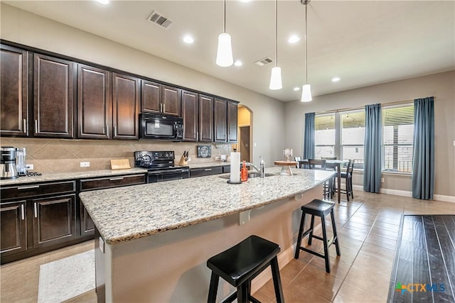 822 Old World Dr, Harker Heights, TX 76548 - kitchen with black appliances, arched walkways, a kitchen breakfast bar, light stone countertops, and a kitchen island with sink