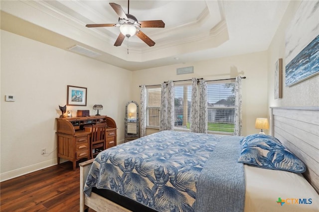 bedroom with crown molding, a tray ceiling, dark hardwood / wood-style flooring, and ceiling fan