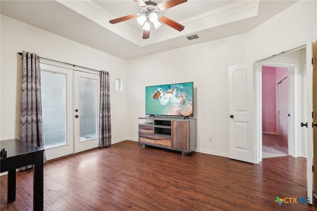 living room featuring a tray ceiling, french doors, dark wood-type flooring, and crown molding