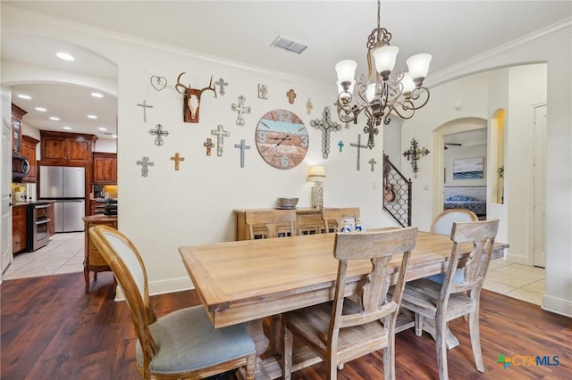 dining space with a notable chandelier, light wood-type flooring, and crown molding