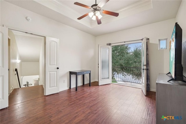 interior space with a raised ceiling, ceiling fan, dark hardwood / wood-style flooring, and access to exterior