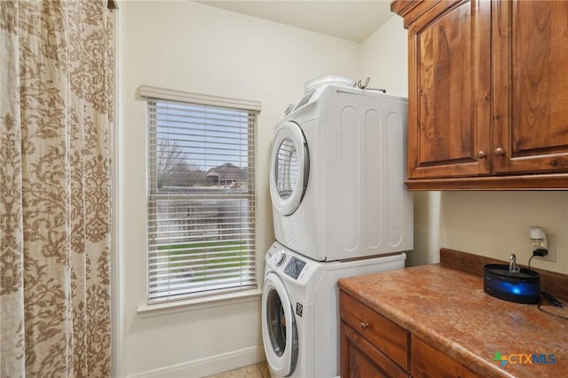 washroom featuring cabinets and stacked washer / drying machine