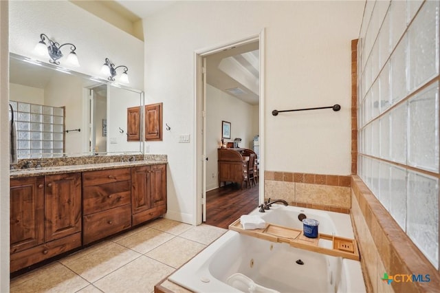 bathroom featuring tile patterned flooring, vanity, and tiled bath