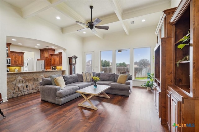 living room featuring a towering ceiling, ceiling fan, coffered ceiling, dark hardwood / wood-style flooring, and beamed ceiling