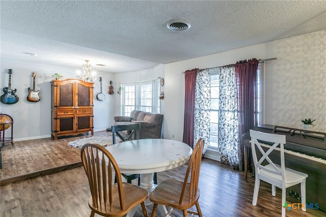 dining room with a notable chandelier, plenty of natural light, a textured ceiling, and dark hardwood / wood-style flooring