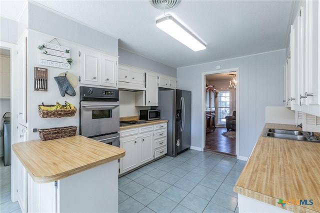 kitchen with sink, light tile patterned floors, appliances with stainless steel finishes, kitchen peninsula, and white cabinets