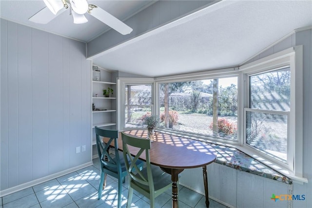 tiled dining space featuring ceiling fan, lofted ceiling, wooden walls, and built in features