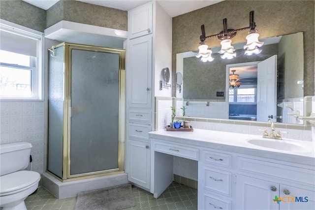 bathroom with vanity, a healthy amount of sunlight, toilet, and a shower with shower door