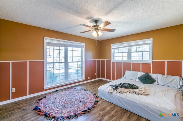 bedroom featuring dark hardwood / wood-style flooring, a textured ceiling, and ceiling fan