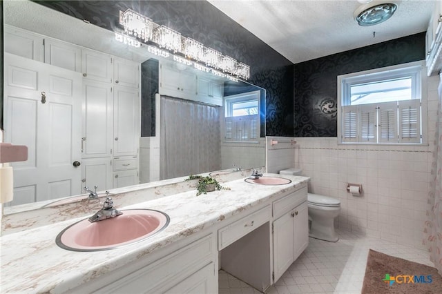 bathroom with vanity, toilet, tile walls, and plenty of natural light