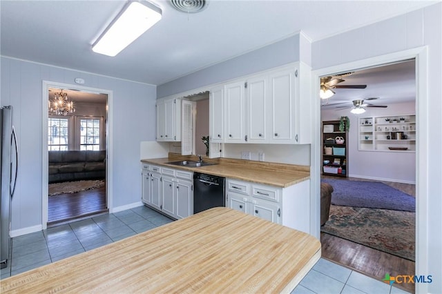 kitchen featuring light tile patterned floors, sink, stainless steel fridge, white cabinetry, and black dishwasher