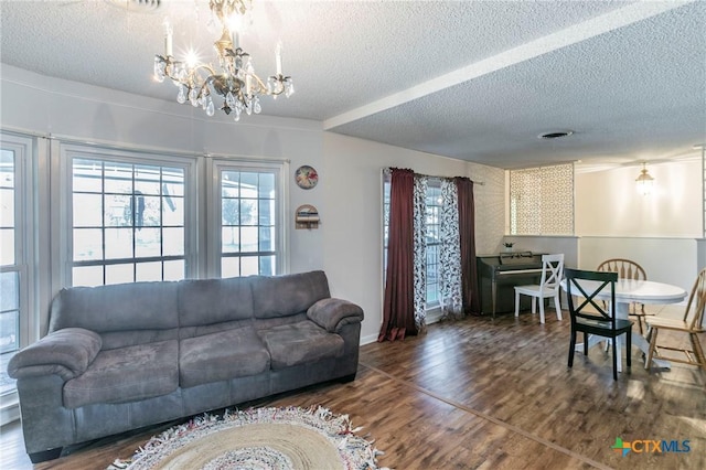 living room featuring an inviting chandelier, dark hardwood / wood-style floors, and a textured ceiling