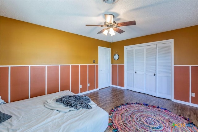 bedroom with dark wood-type flooring, ceiling fan, a closet, and a textured ceiling