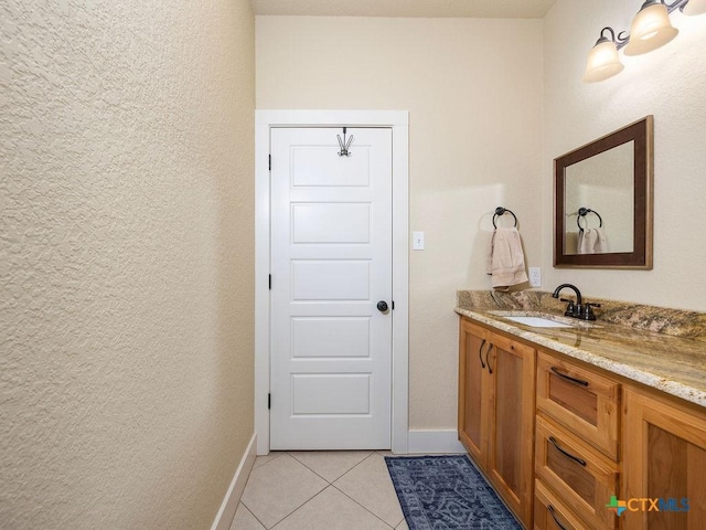 bathroom with vanity, baseboards, and tile patterned floors