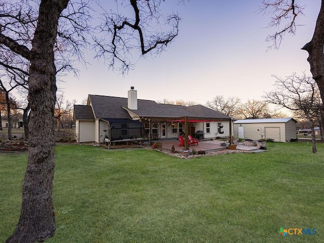 rear view of property with a yard, an outdoor structure, a chimney, and a wooden deck