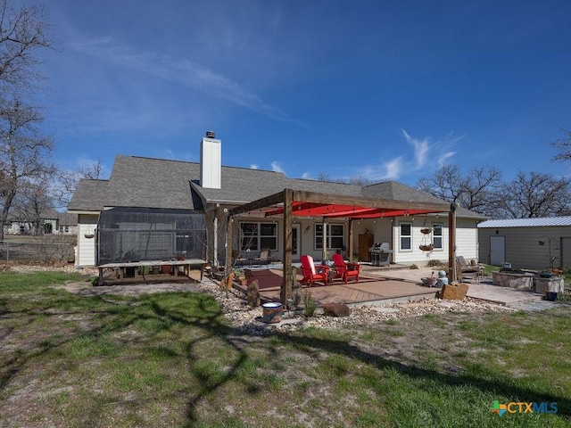 rear view of property with a deck, a yard, a chimney, and fence