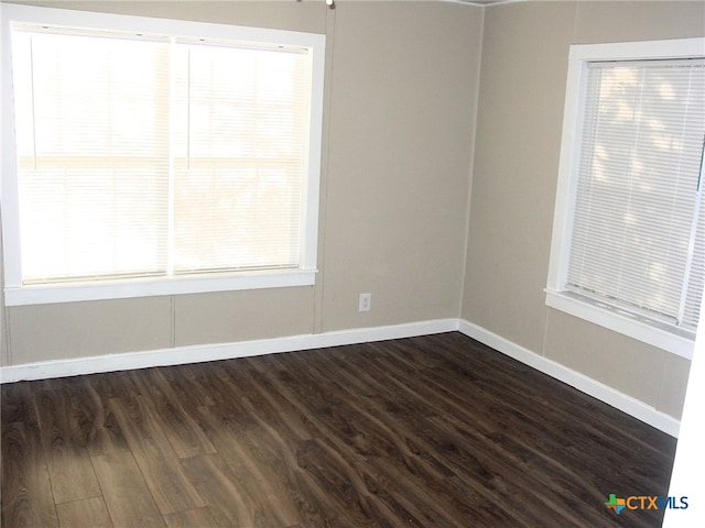 unfurnished room with a wealth of natural light and dark wood-type flooring