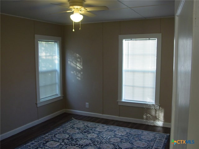 empty room featuring plenty of natural light, dark hardwood / wood-style floors, and ceiling fan