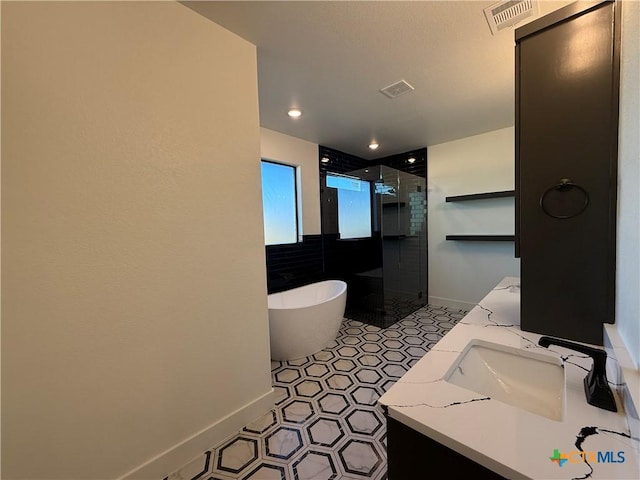 bathroom with tile patterned floors, vanity, and shower with separate bathtub