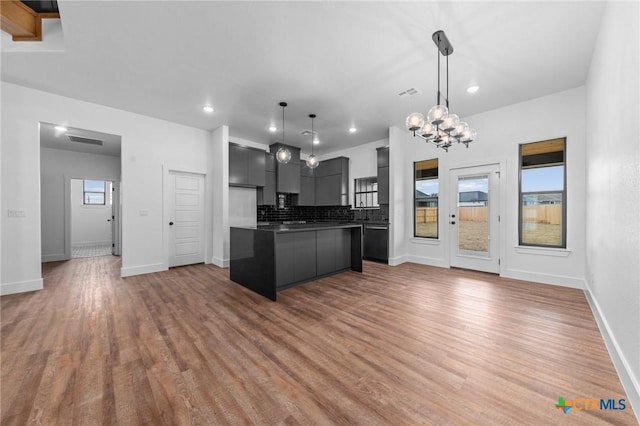 kitchen featuring wood-type flooring, backsplash, pendant lighting, and a kitchen island