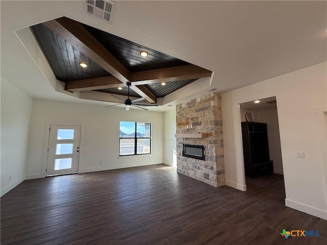 unfurnished living room with dark hardwood / wood-style floors, coffered ceiling, a stone fireplace, and beam ceiling