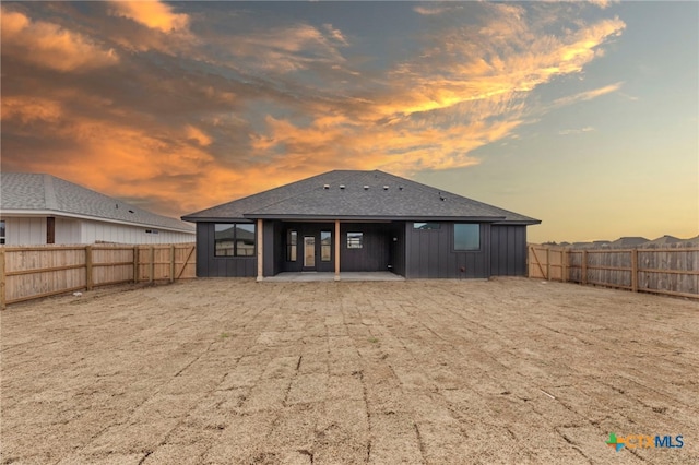 back house at dusk featuring a patio area