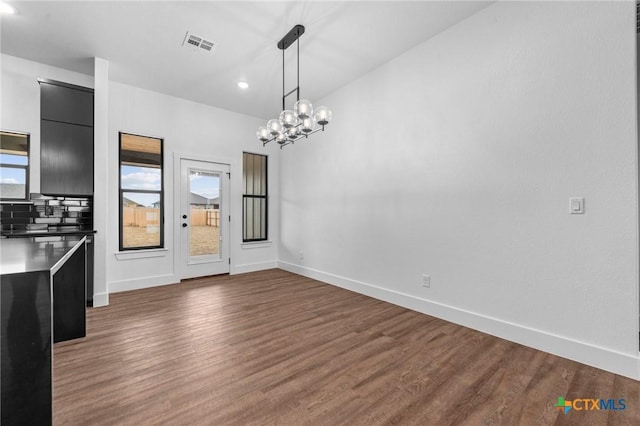 unfurnished dining area featuring dark hardwood / wood-style flooring and an inviting chandelier