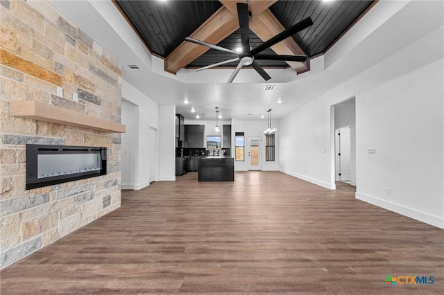 unfurnished living room featuring ceiling fan, dark hardwood / wood-style flooring, beamed ceiling, coffered ceiling, and a stone fireplace