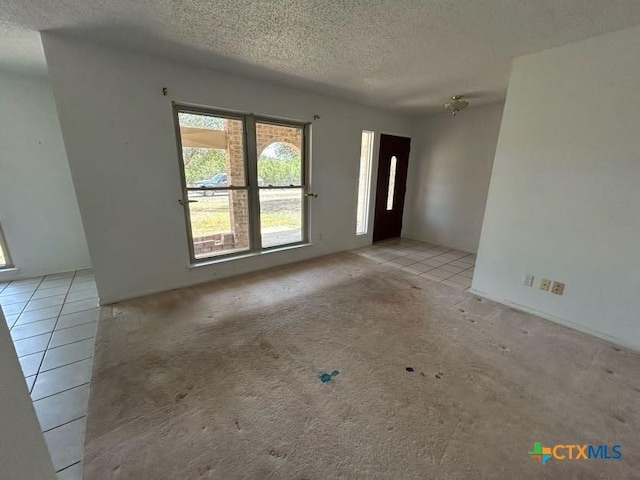 tiled foyer with carpet flooring and a textured ceiling