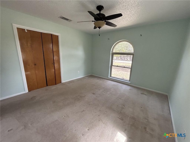 unfurnished bedroom featuring visible vents, a ceiling fan, a textured ceiling, carpet flooring, and a closet