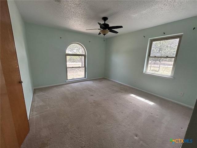 carpeted empty room featuring a ceiling fan, baseboards, and a textured ceiling