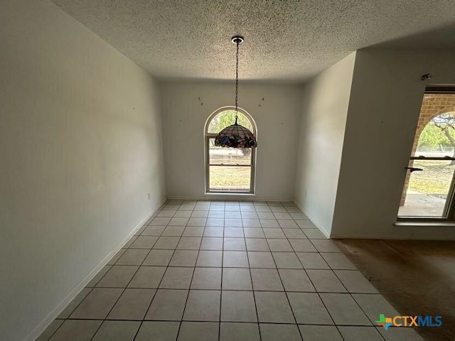 interior space featuring a textured ceiling, baseboards, and light tile patterned floors