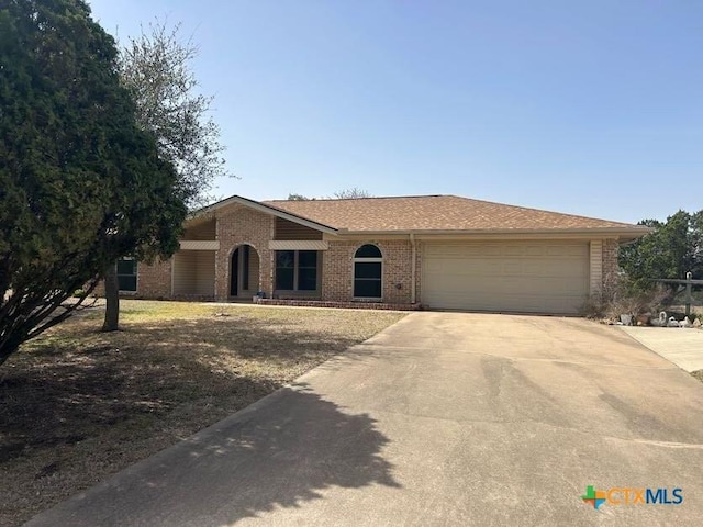 ranch-style home with a garage, driveway, and brick siding