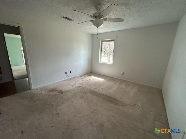 carpeted spare room with ceiling fan, visible vents, and a textured ceiling