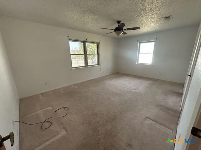 unfurnished room with a ceiling fan, visible vents, a textured ceiling, and carpet flooring