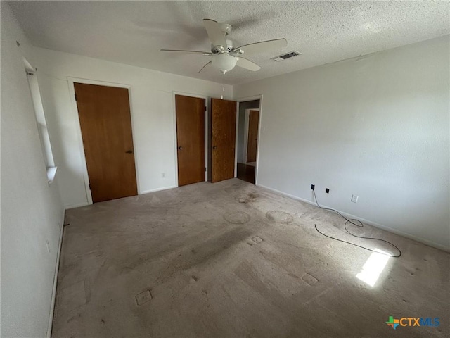 unfurnished bedroom with a ceiling fan, visible vents, and a textured ceiling