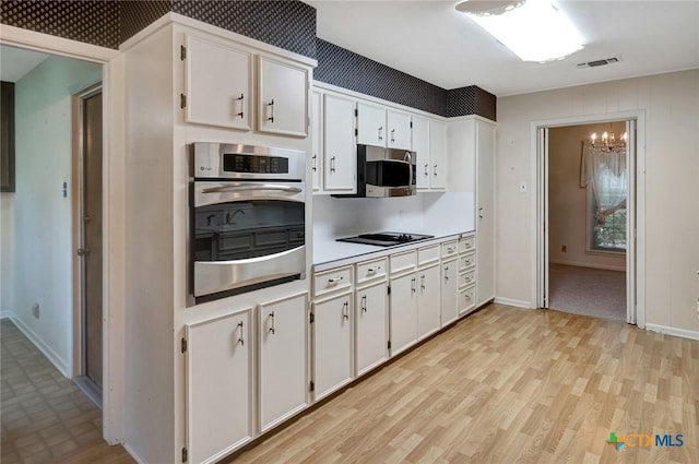 304 Simpson Rd, Victoria, TX 77904 - kitchen featuring appliances with stainless steel finishes, white cabinets, a chandelier, light wood-style floors, and light countertops