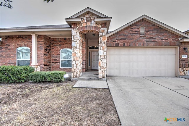 view of front of property with a garage, concrete driveway, brick siding, and stone siding