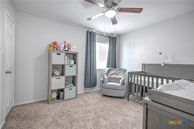 bedroom with a crib, carpet, baseboards, and ceiling fan