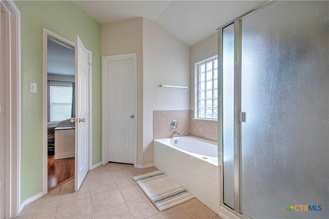 bathroom with a stall shower, baseboards, lofted ceiling, tile patterned floors, and a bath