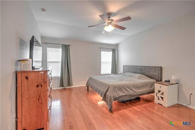 bedroom featuring lofted ceiling, light wood-style flooring, multiple windows, and baseboards