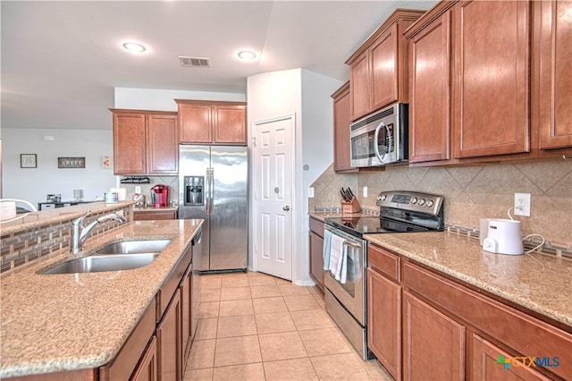 kitchen featuring light tile patterned floors, stainless steel appliances, tasteful backsplash, visible vents, and a sink