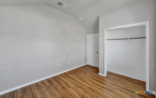 unfurnished bedroom featuring a closet, lofted ceiling, and hardwood / wood-style flooring